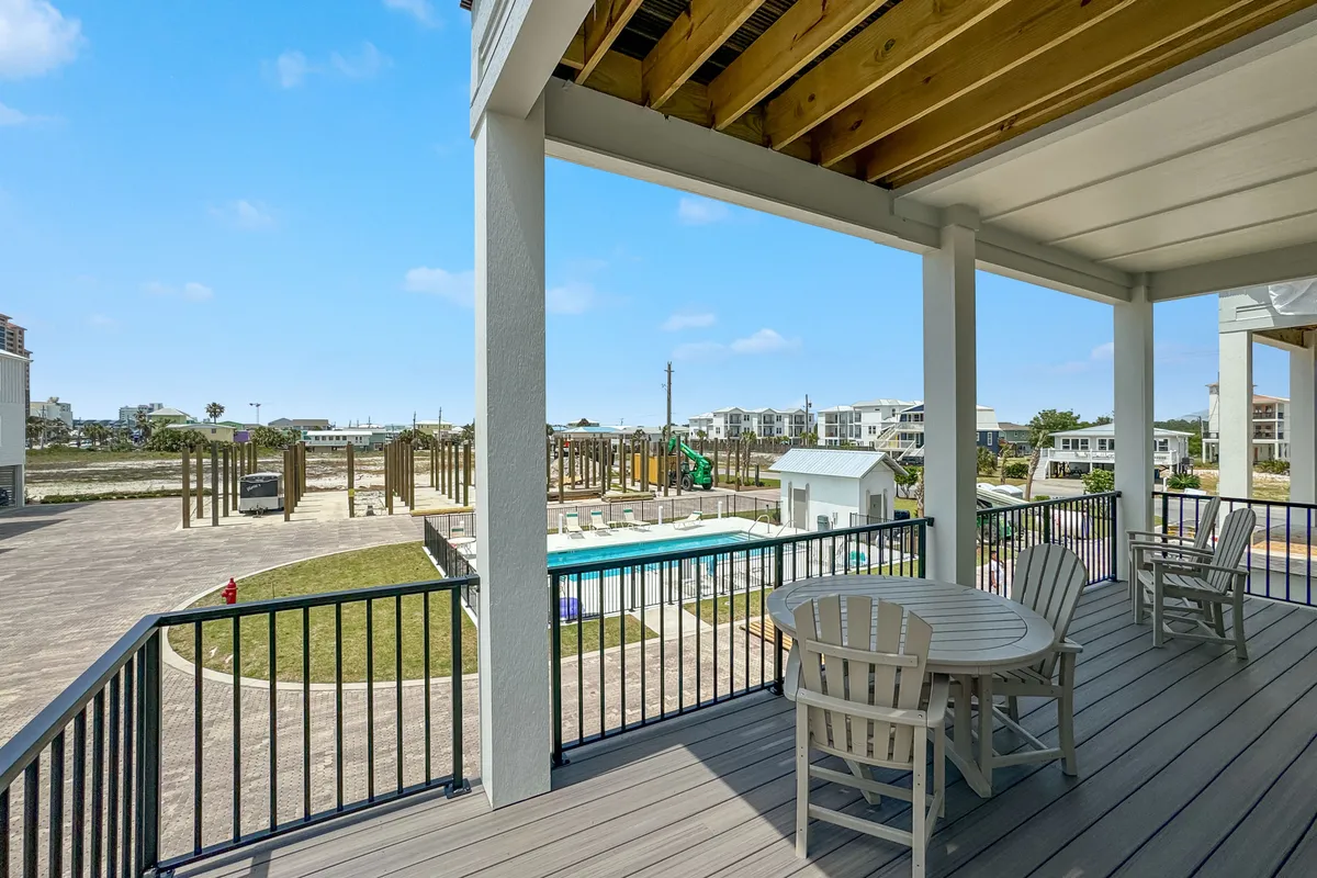 This exterior scene showcases an inviting outdoor seating area next to a swimming pool, with playground equipment and surrounding houses visible. The area is lively, family-friendly, and perfect for social gatherings, children’s play, or enjoying the outdoors. The combination of pool, porch, and amenities conveys a resort-like community environment.