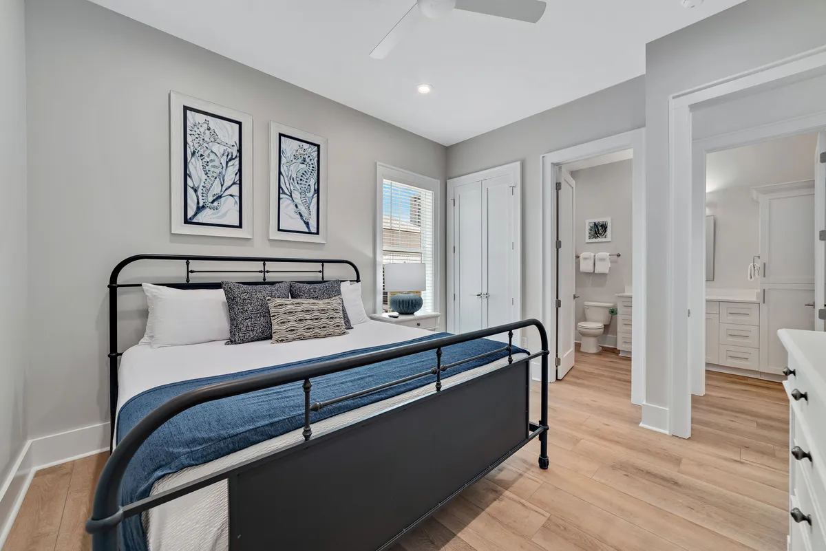 A tranquil bedroom with a metal bed frame, textured throw pillows, and large windows that fill the room with natural light. The decor balances comfort and style, offering a restful retreat.