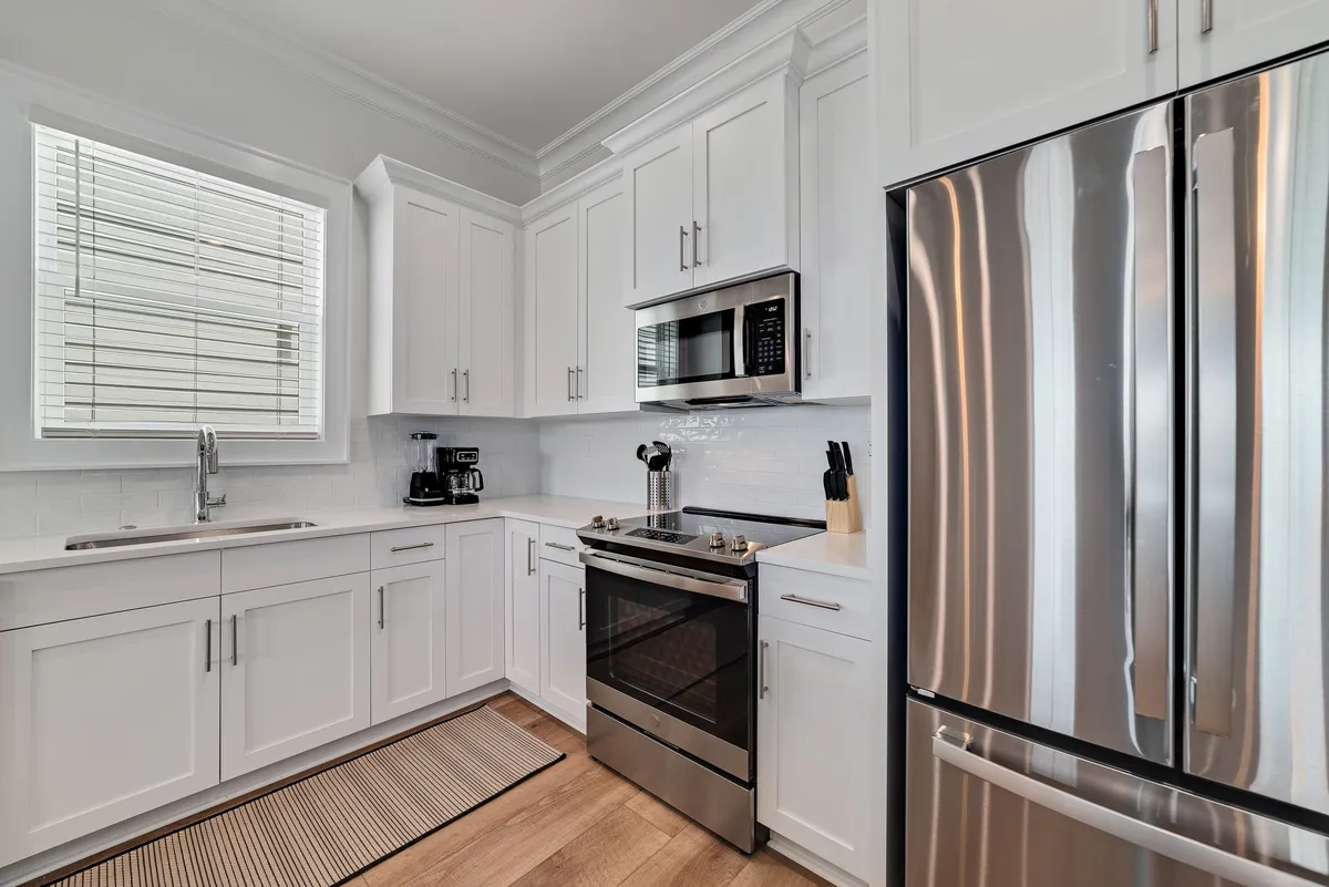 A sleek, well-equipped kitchen with stainless steel appliances, white cabinetry, and ample counter space. The organized layout and sophisticated details support easy meal preparation, morning coffees, and group breakfasts before setting out for Gulf Shores activities.